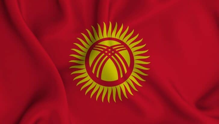 The Kyrgyz flag with a red background, featuring a yellow sun with 40 points and intersecting lines in the center
