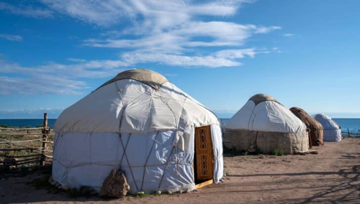 Traditional yurts set against a landscape with a blue sky and distant mountains, related to Kyrgyzstan culture