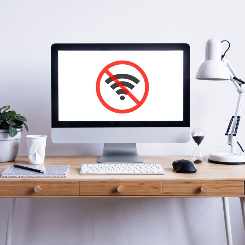 Desktop computer on a wooden desk displaying a no WiFi symbol