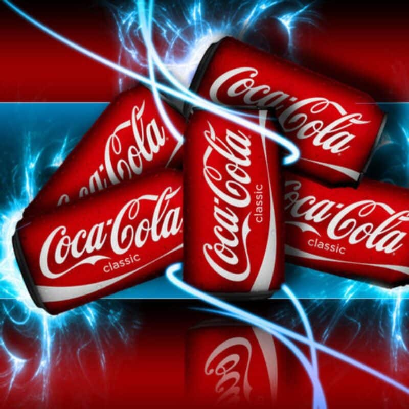 Coca-Cola cans against a dynamic blue and red background with lighting effects