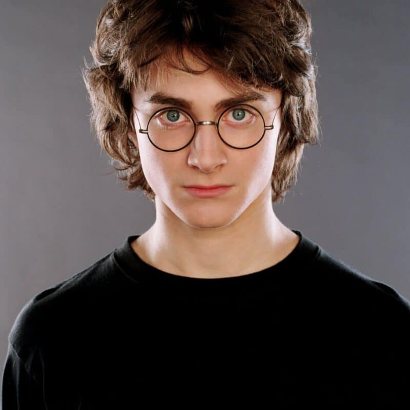 Daniel Radcliffe wearing round glasses and looking directly at the camera