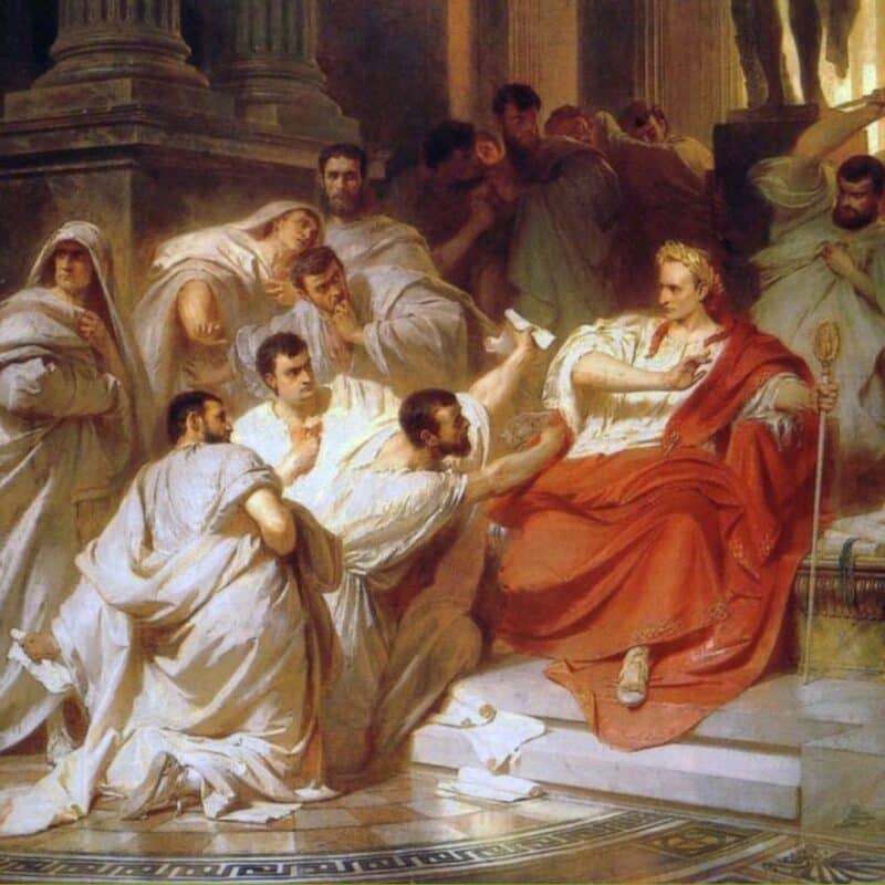 A depiction of Julius Caesar surrounded by Roman senators, with one senator approaching him while he sits in a red robe, illustrating his assassination