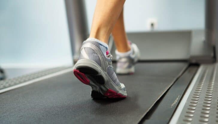 Close-up of a person's feet in athletic shoes running on a treadmill, highlighting joint protection benefits