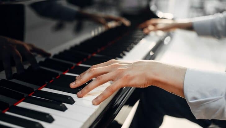 Hands playing a piano keyboard, illustrating the instrument's broad range