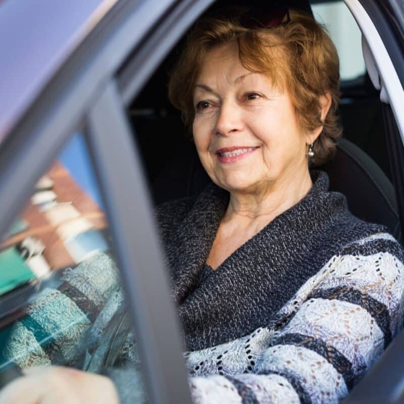 A smiling elderly woman sitting in a car