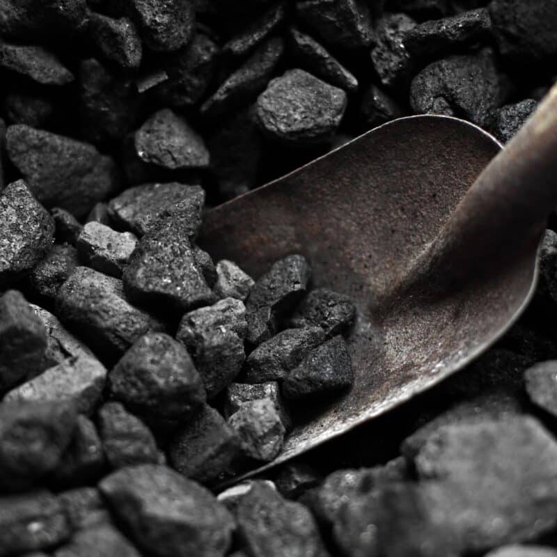 A metal shovel resting in a pile of coal