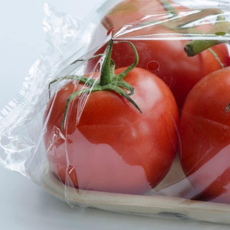 Red tomatoes wrapped in transparent cellophane on a tray