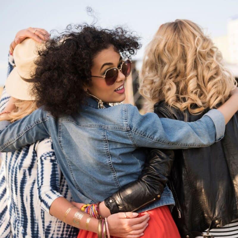 Three friends embracing outdoors, showcasing a bond of friendship and social connection