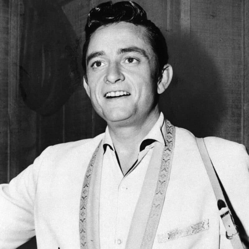 Johnny Cash smiling and wearing a light-colored suit jacket
