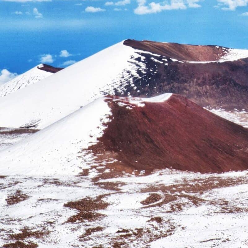 Snow-covered peaks of Mauna Kea in Hawaii under a blue sky