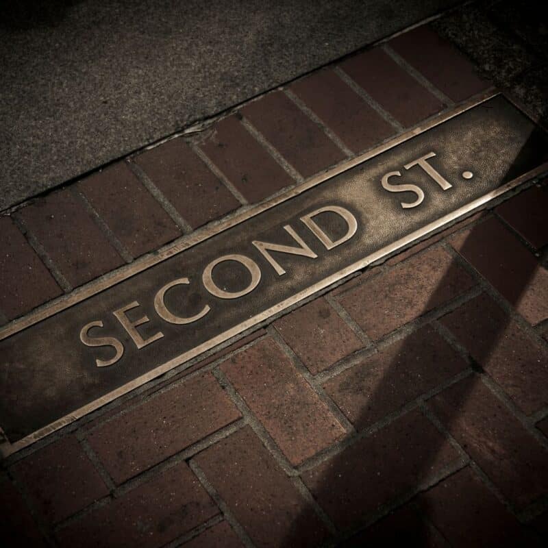 Street sign reading "Second St." embedded in a brick sidewalk