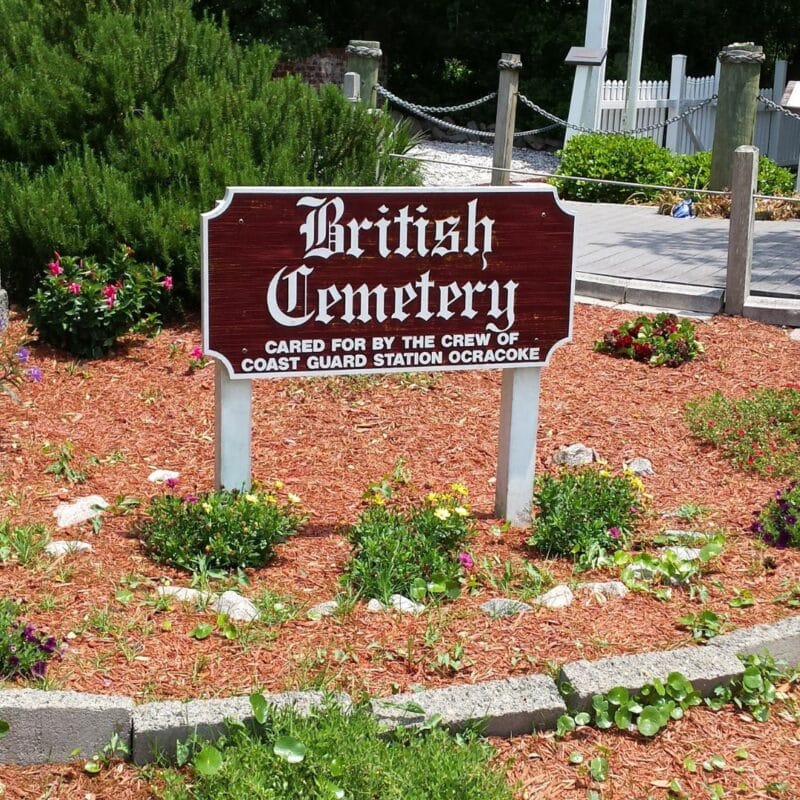 Sign reading "British Cemetery" surrounded by flowers and greenery