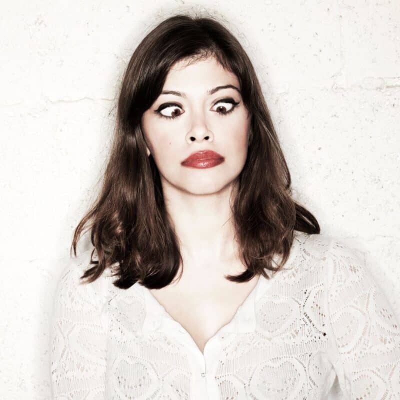 A woman with long brown hair and red lipstick crossing her eyes