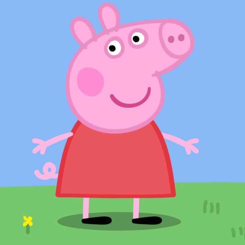 Peppa Pig standing on grass under a blue sky
