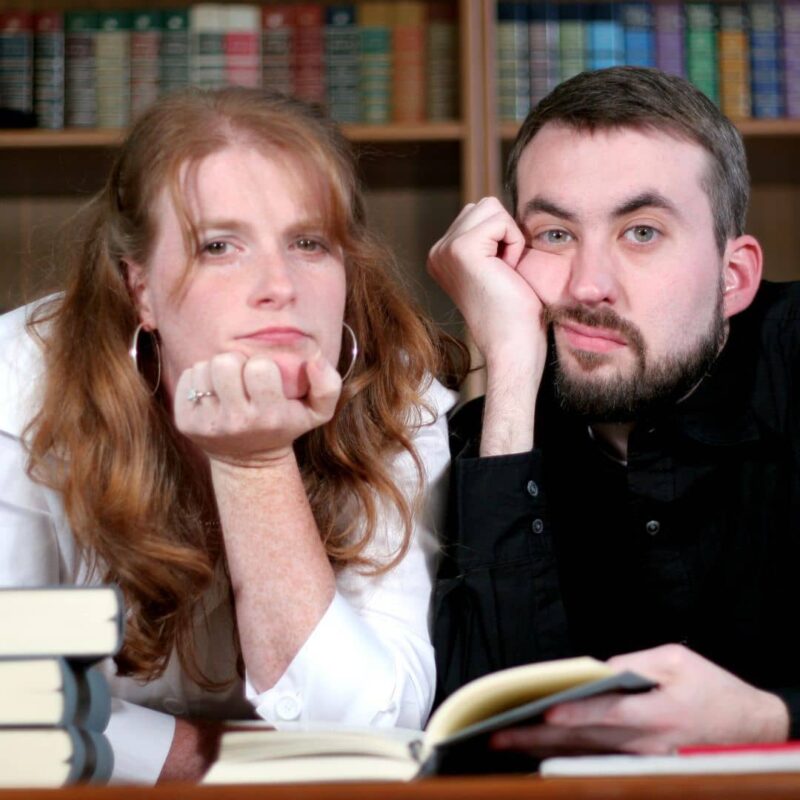 Two people resting their chins on their hands with bored expressions