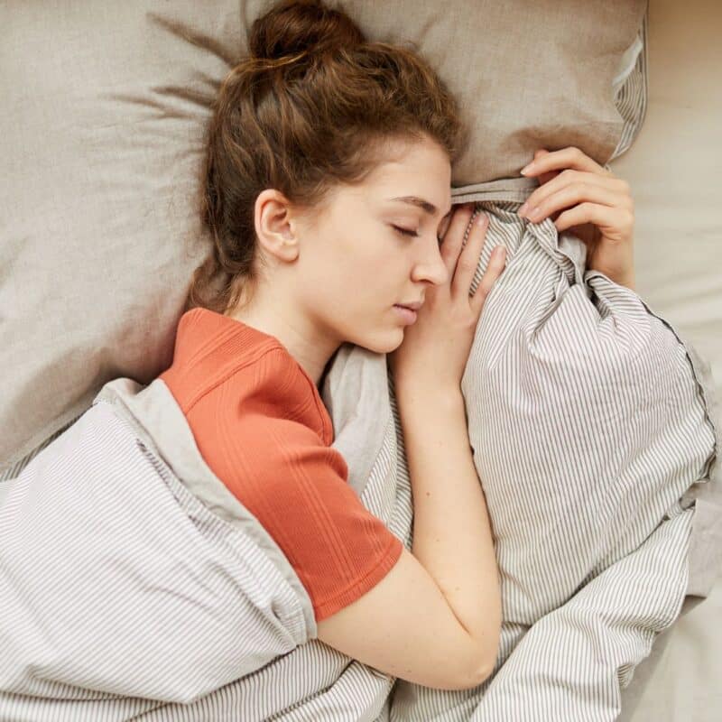 A person sleeping peacefully under a weighted blanket