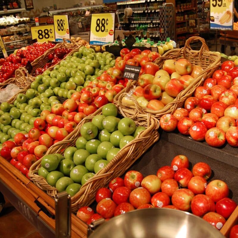 Variety of apples displayed in baskets at a supermarket produce section
