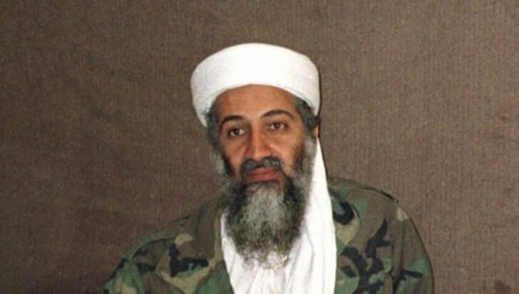 Osama Bin Laden wearing a white turban and camouflage jacket,