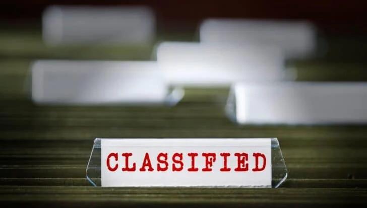 A sign with the word 'CLASSIFIED' prominently displayed, symbolizing the secretive nature of the CIA