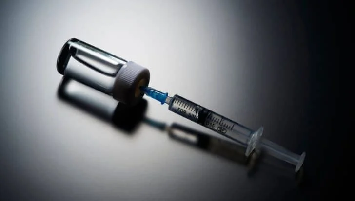 A syringe filled with liquid is attached to a vial, relevant to the CIA's use of a fake vaccine program for espionage purposes