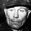 Ed Gein wearing a cap, being arrested