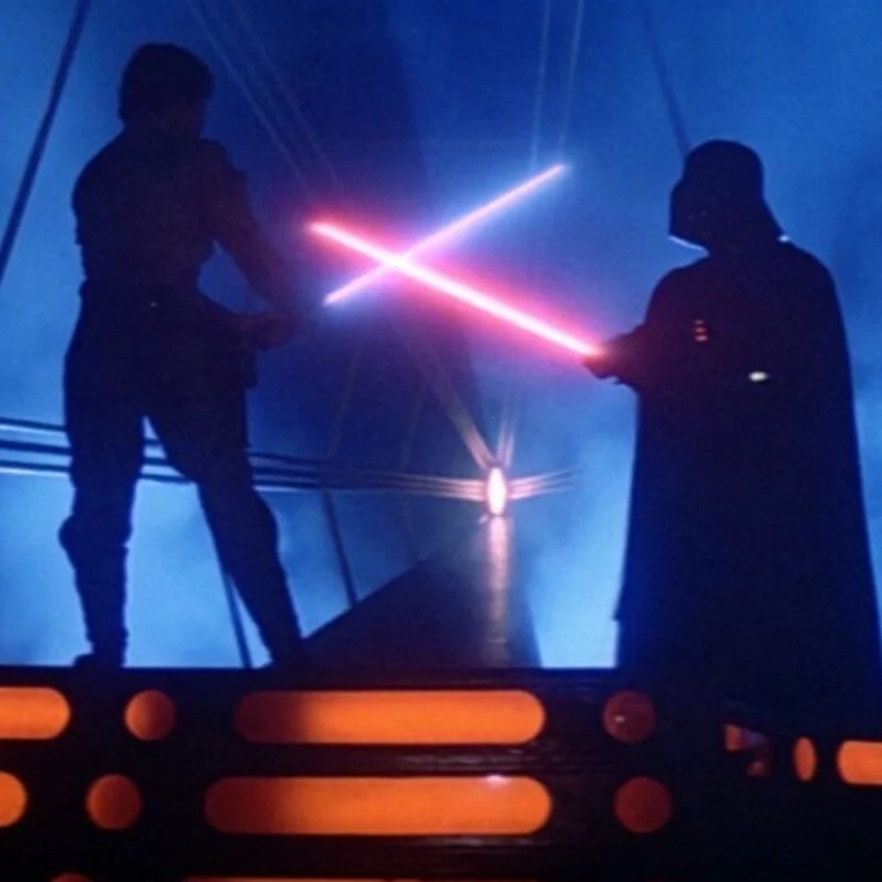 Luke Skywalker and Darth Vader clash lightsabers in a dark, smoky setting